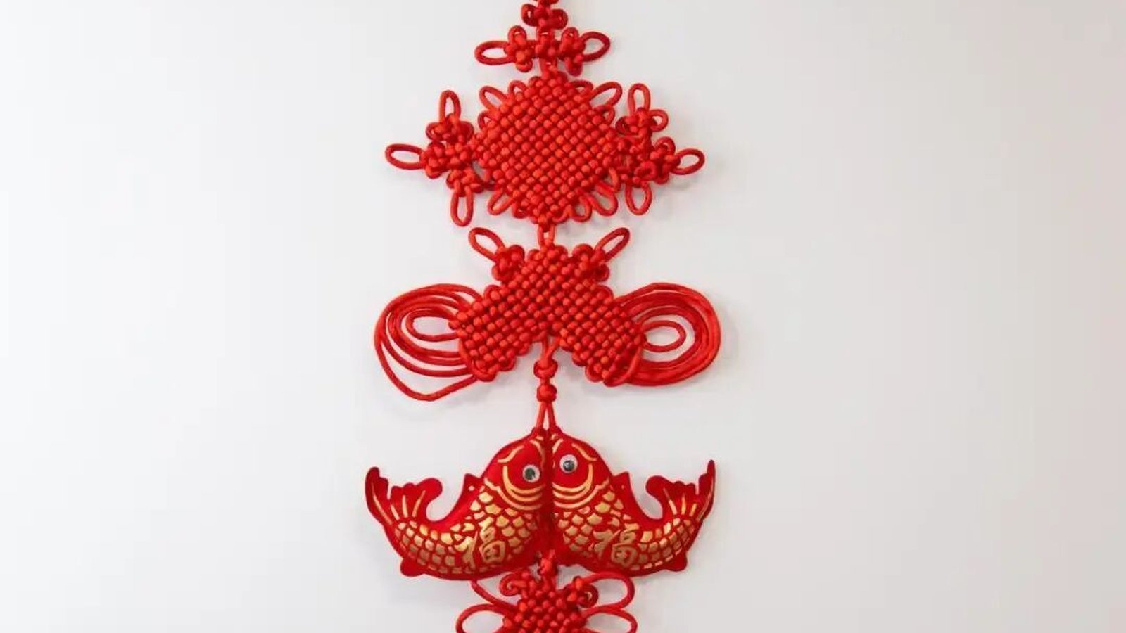 A wall hanging combining pan chang knots with a pair of red-and-gold fish, a compound blessing for abundance
