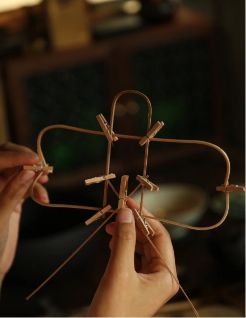 Binding a small bamboo kite frame, with the joints held by clips while the thread is tied