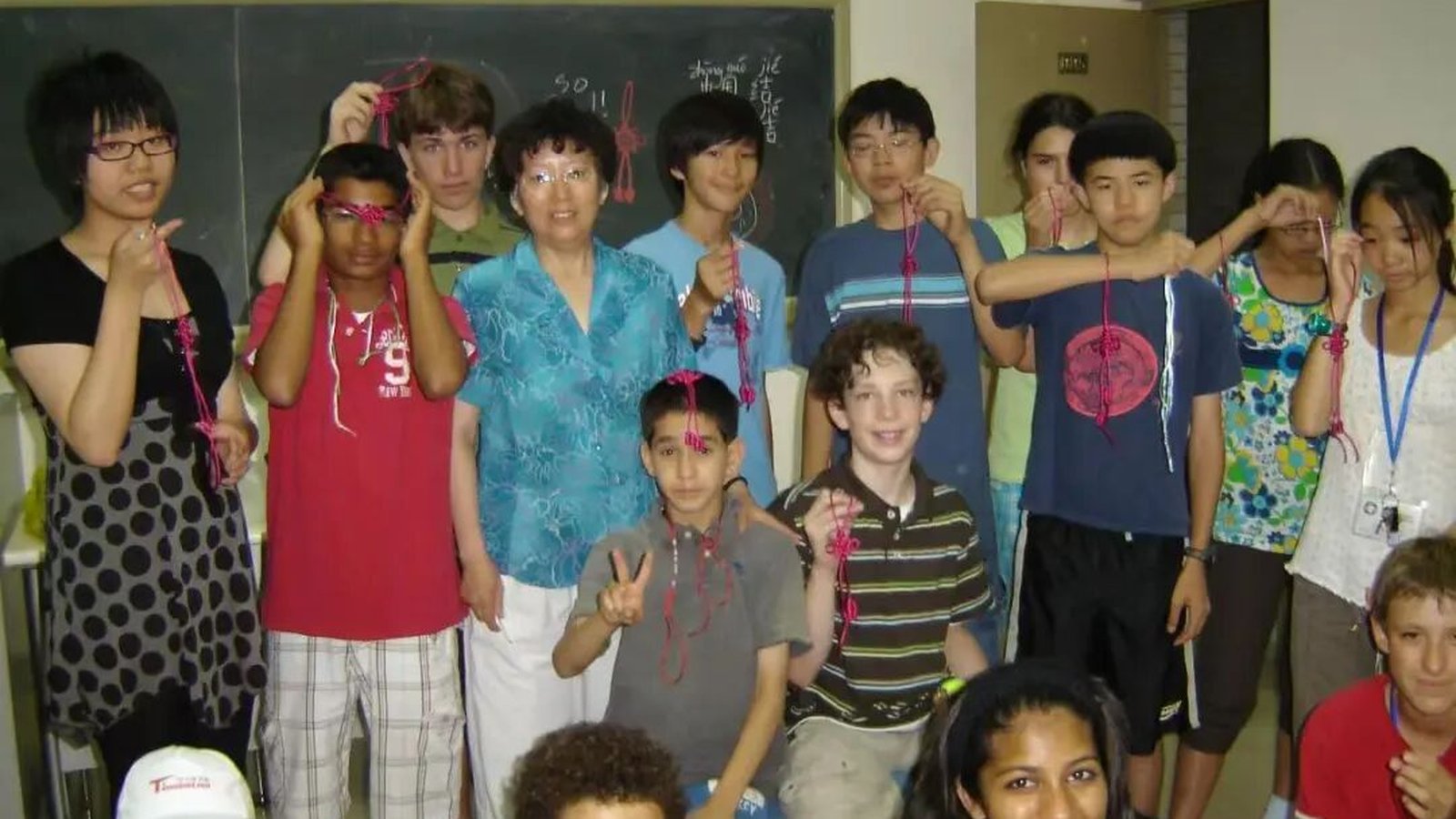 Mi Lingzhu with a class of international students, each holding up the small red Chinese knot they just tied