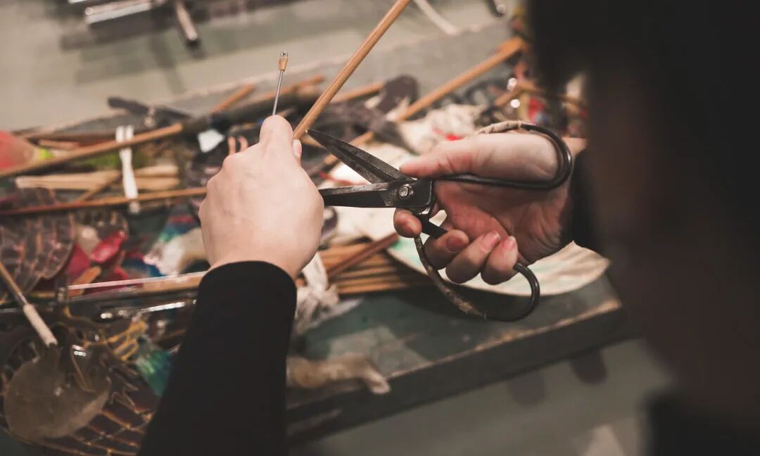 Sun Bingqing trimming puppet parts at her cluttered workbench